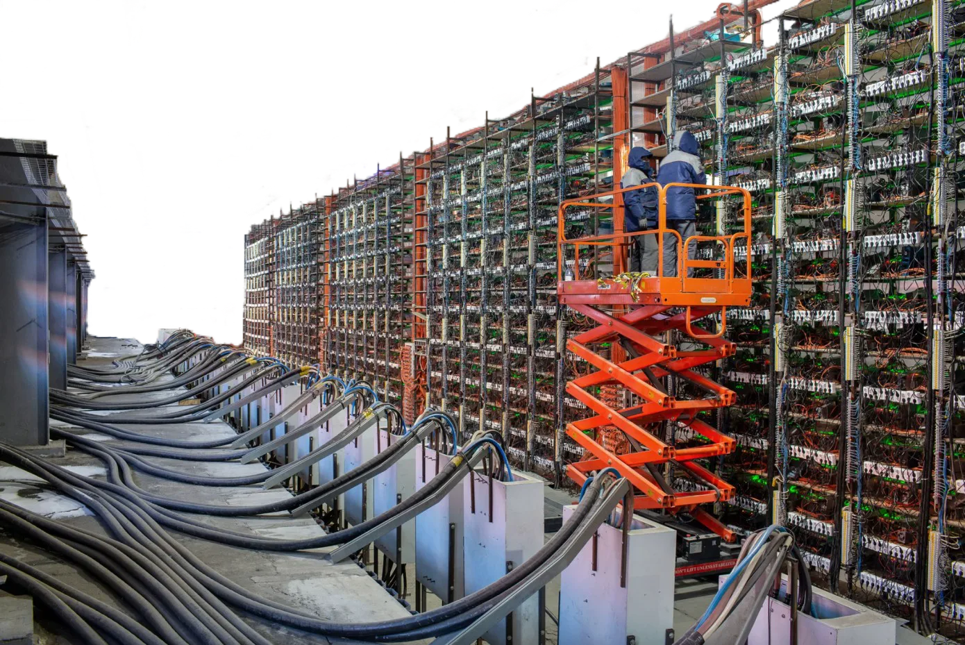 Green Bitcoin Mining 2 Workers on a lift maintaining rows of ASIC Bitcoin mining machines in a large mining farm