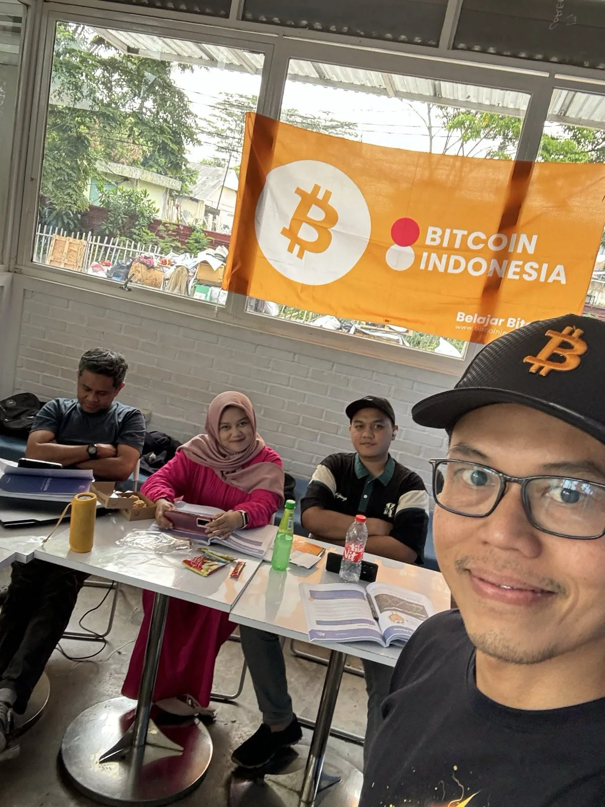 My First Bitcoin instructor taking a selfie with students in front of a Bitcoin Indonesia banner
