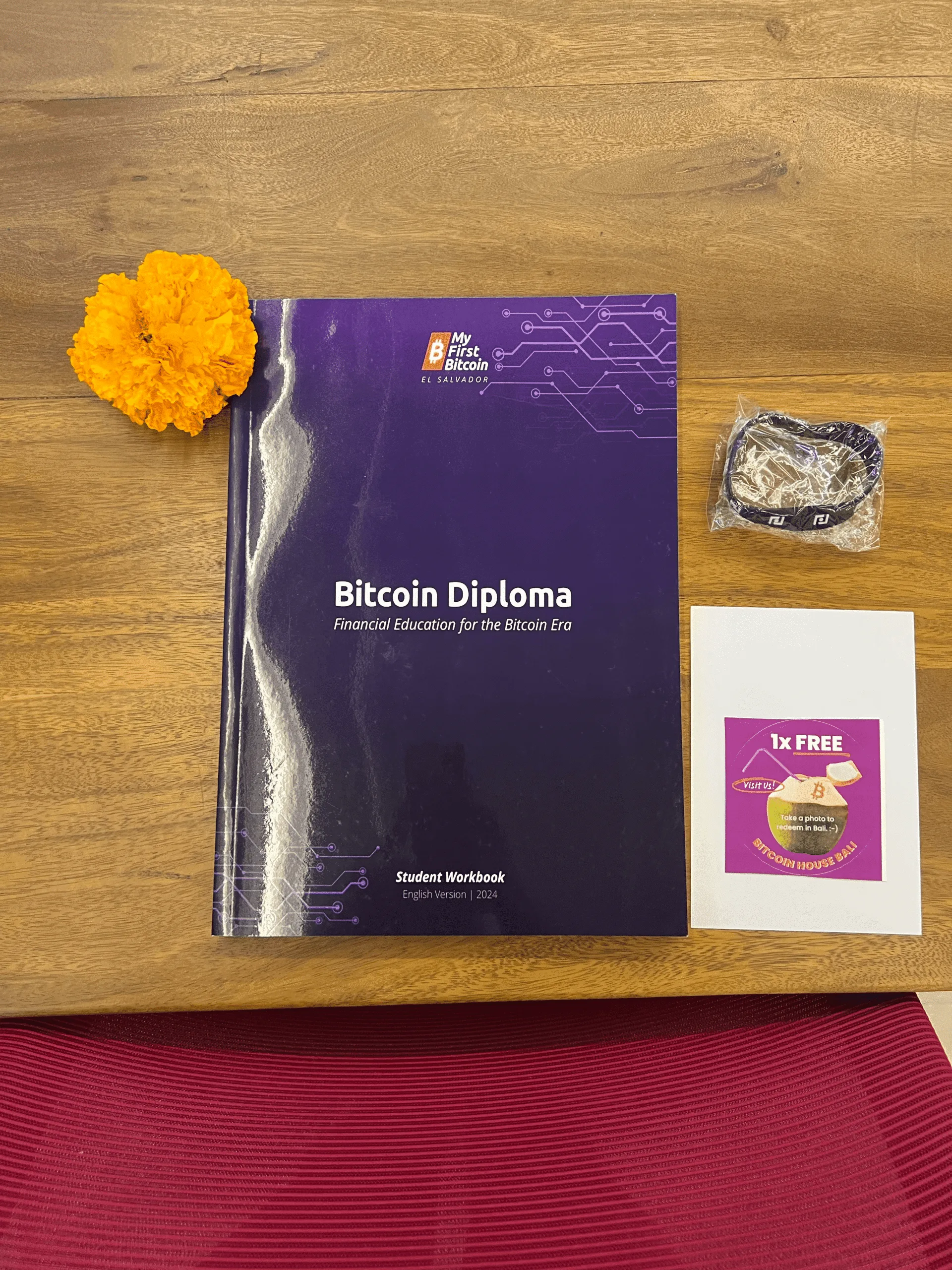 My First Bitcoin Diploma student workbook next to a flower and a free coconut drink voucher for Bitcoin House Bali