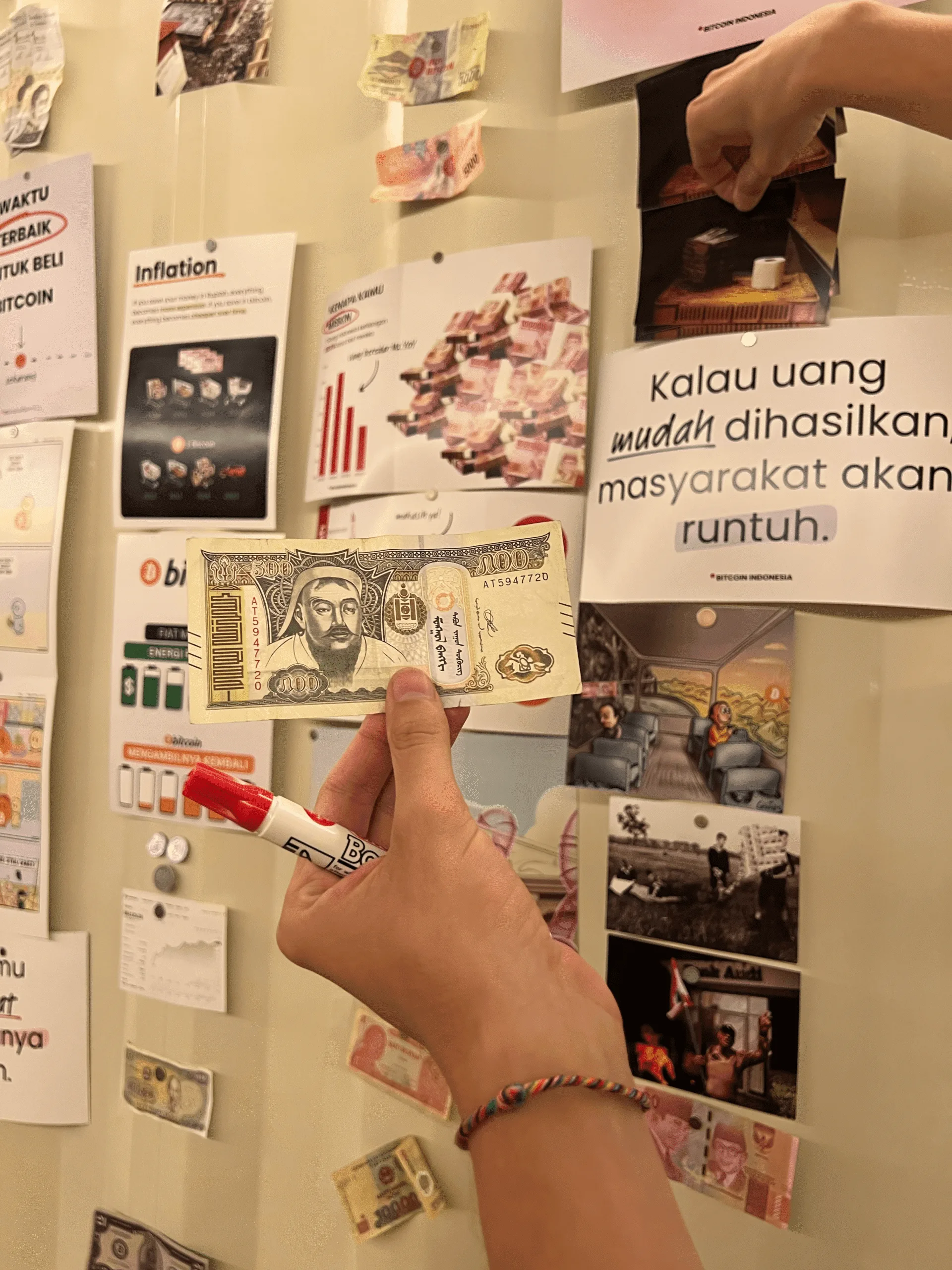 Educational wall display comparing inflation and fiat money to Bitcoin, with a historical banknote held up for comparison