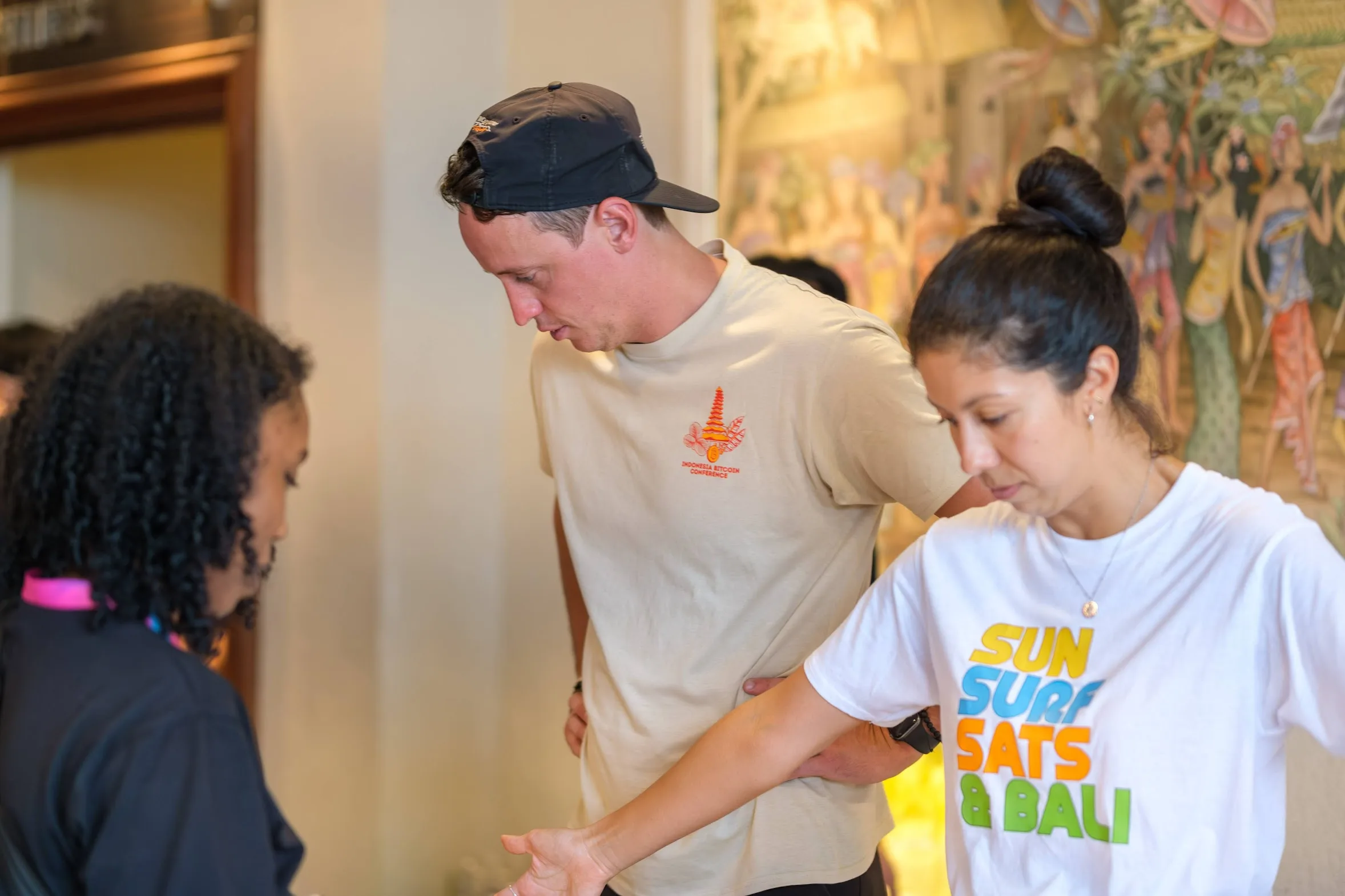 Two attendees at the Indonesia Bitcoin Conference, one wearing a conference t-shirt, the other wearing a Sun Surf Sats and Bali t-shirt