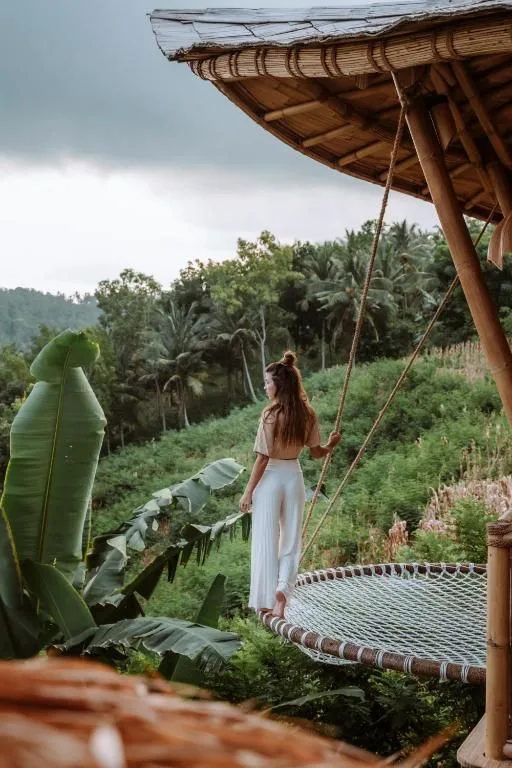 A woman on a giant rope swing overlooking rice terraces and jungle near a resort in Bali