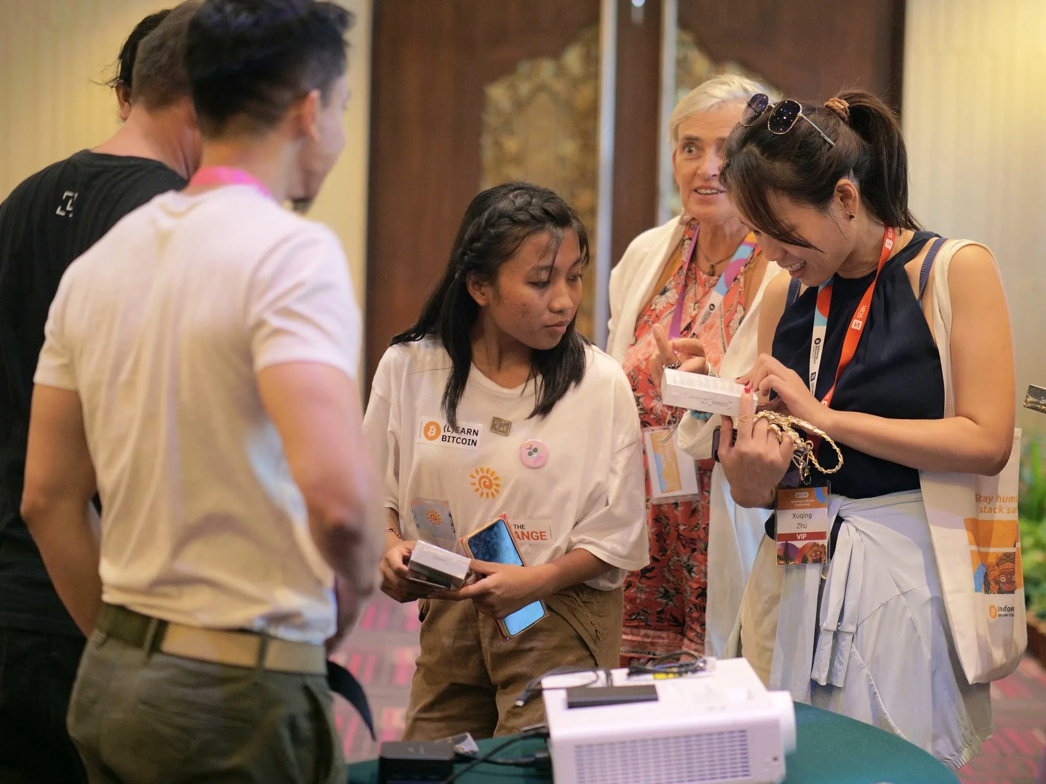 Conference attendees examining a hardware wallet at an expo table