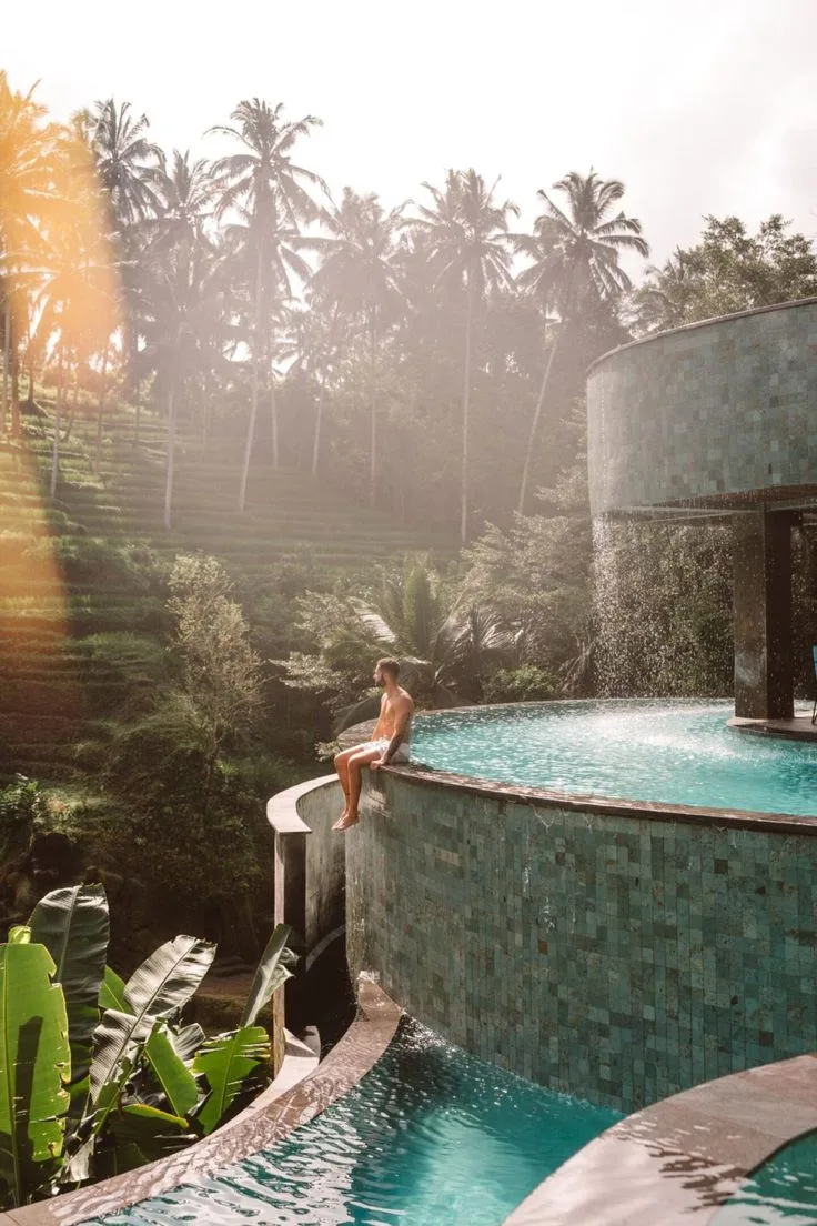A man sitting at the edge of an infinity pool overlooking the Ubud jungle and rice terraces