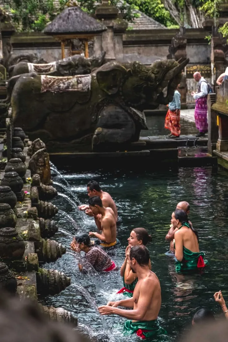 People participating in a traditional Balinese water blessing ceremony at a temple